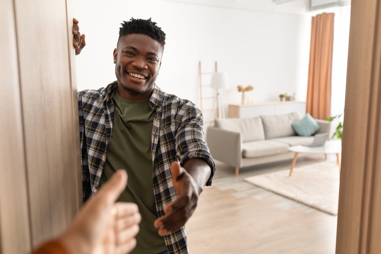 Renter shaking hands with landlord at the door and smiling